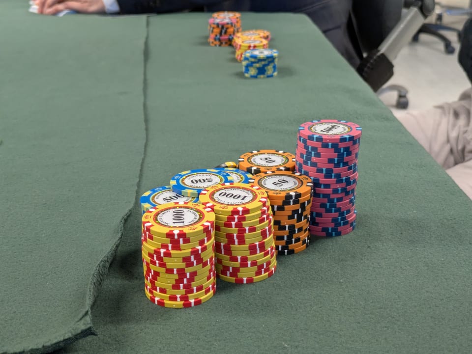 Tall stacks of poker chips on green felt, sorted by denomination, with a tower of 5,000 chips